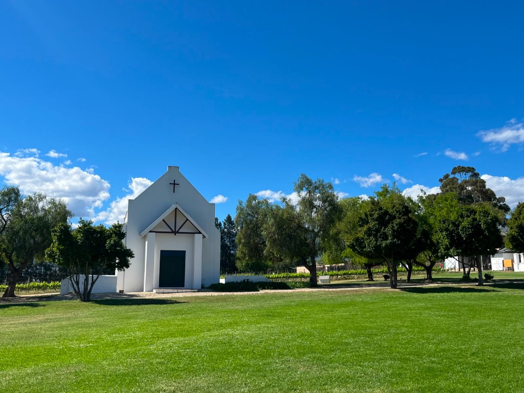 The white chapel at Manley Wine Estate, with lawn, vines and trees